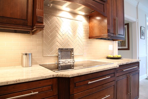 Bianco Romano Granite Countertop with Cream Ceramic Backsplash and Monterey with Black Glaze Cherry Cabinets. Layout is Subway and Herringbone .
